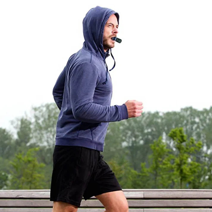 Person wearing a blue hoodie and black shorts running outdoors on a rainy day.
