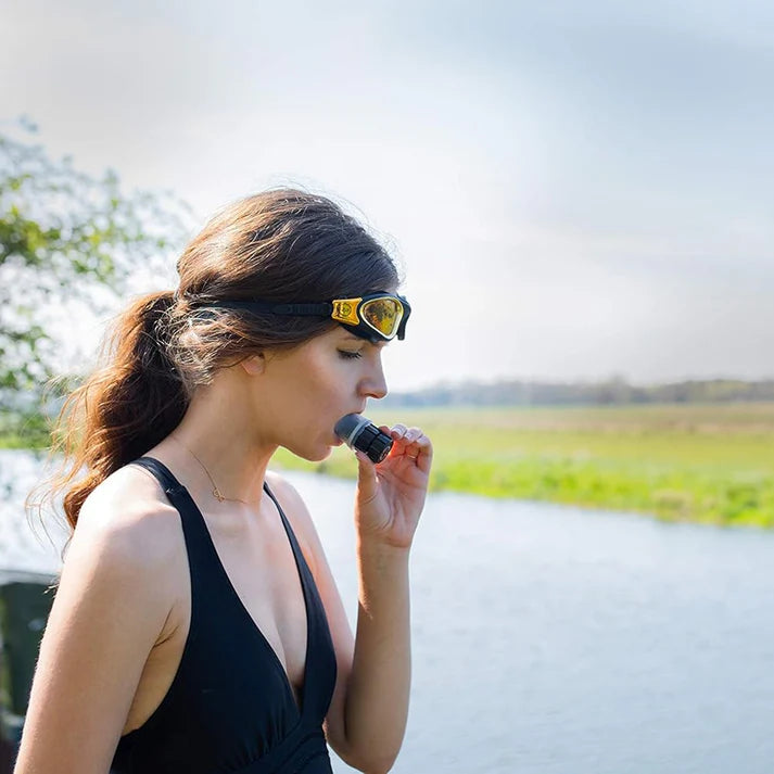 Woman wearing sunglasses and a black dress with a blurred natural background