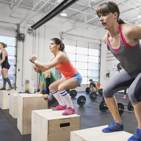 Group of people exercising on boxes in a gym setting